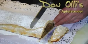 Apfelstrudel alemán casero espolvoreado con azúcar impalpable, recién horneado y cortado en la cocina